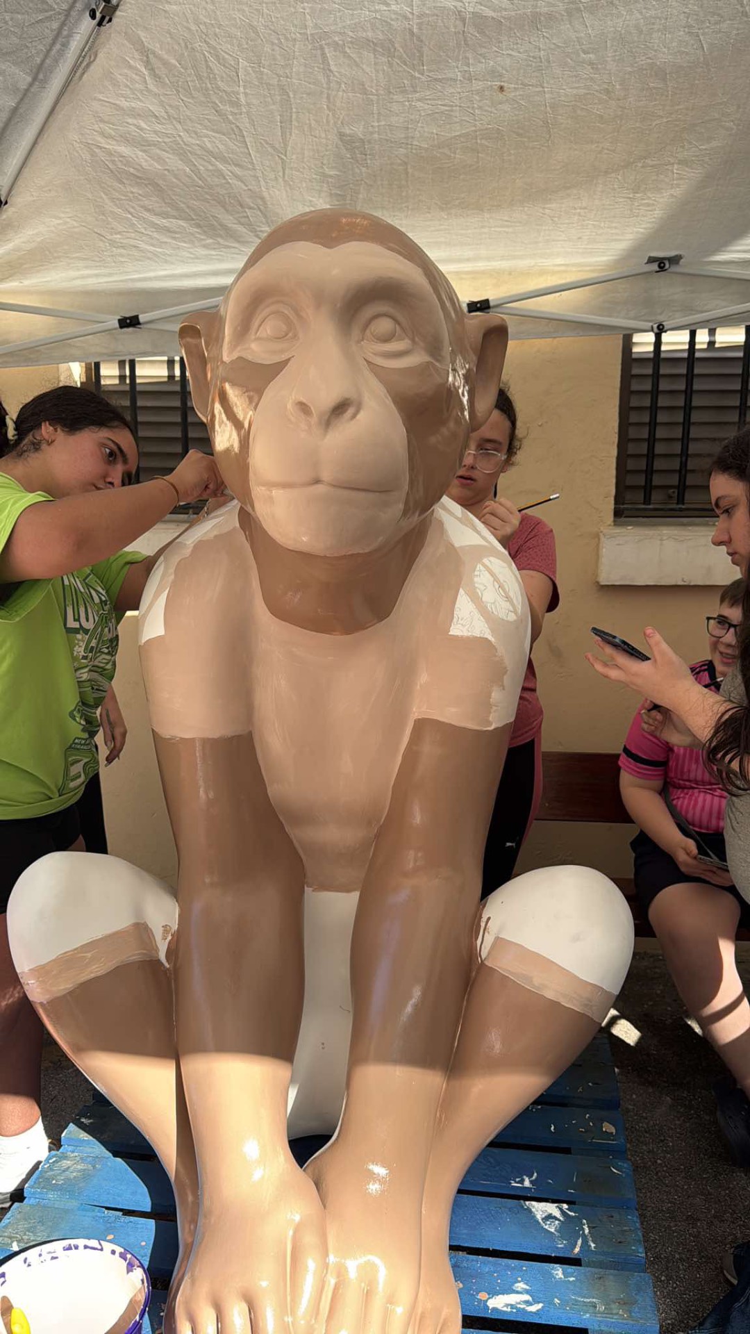 The unpainted Esmeralda sculpture with youth artists preparing to paint