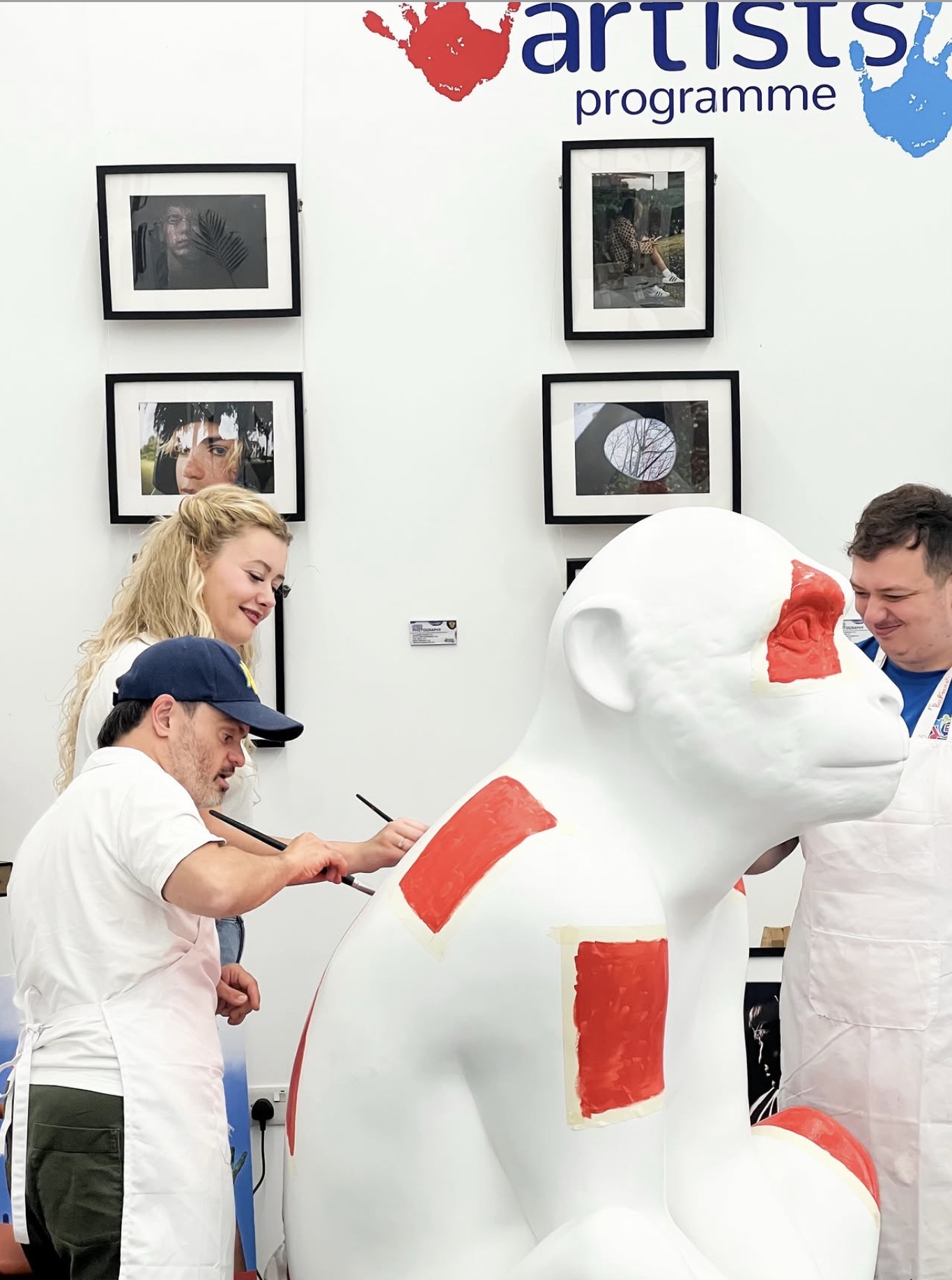 Artists painting a Barbary Macaque sculpture with red details