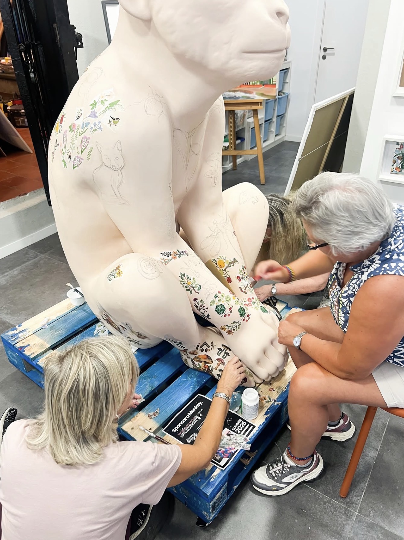 Artists decorating a sculpture with botanical illustrations