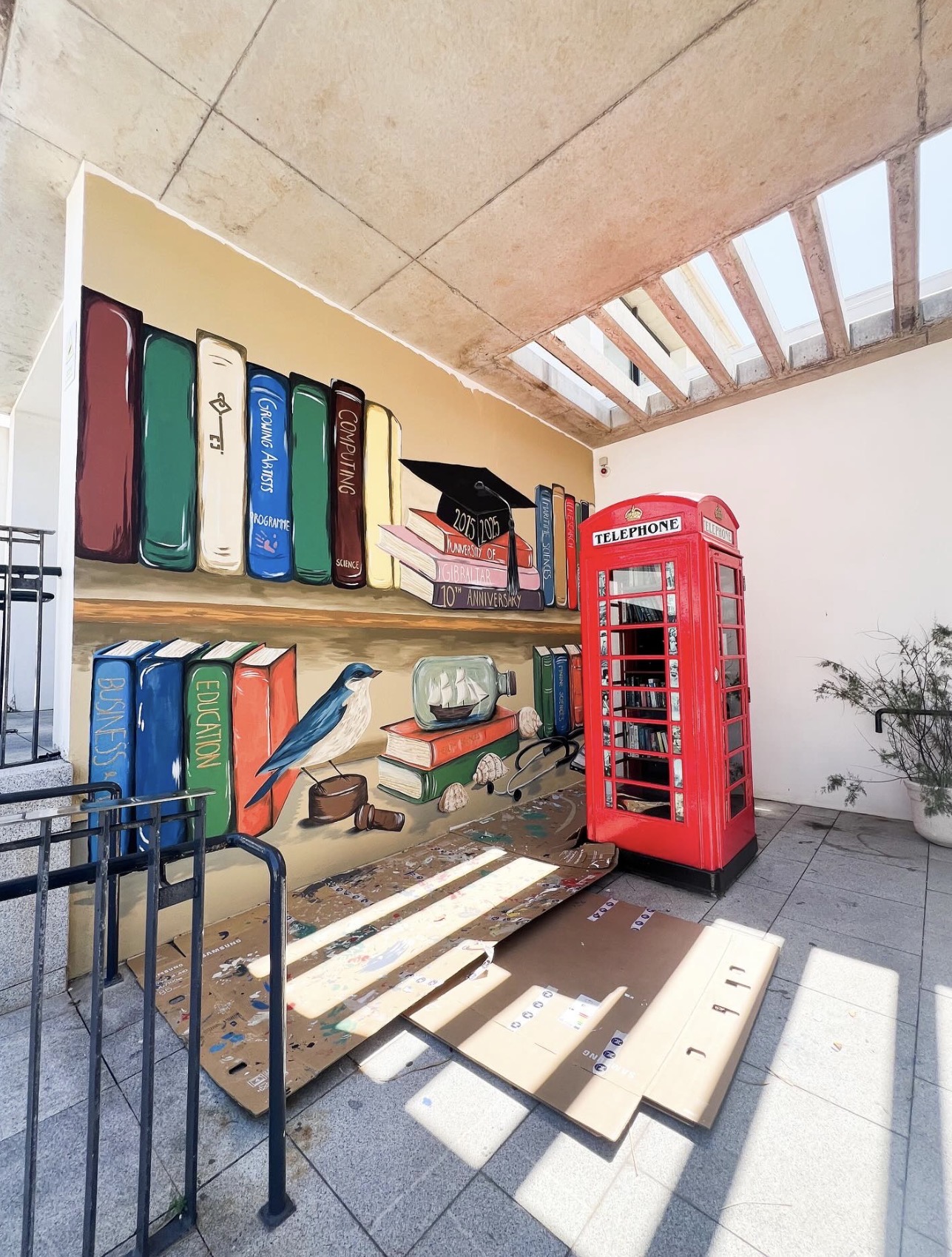Large-scale mural of colourful books, a graduation cap and a bluebird celebrating the University of Gibraltar's 10th anniversary