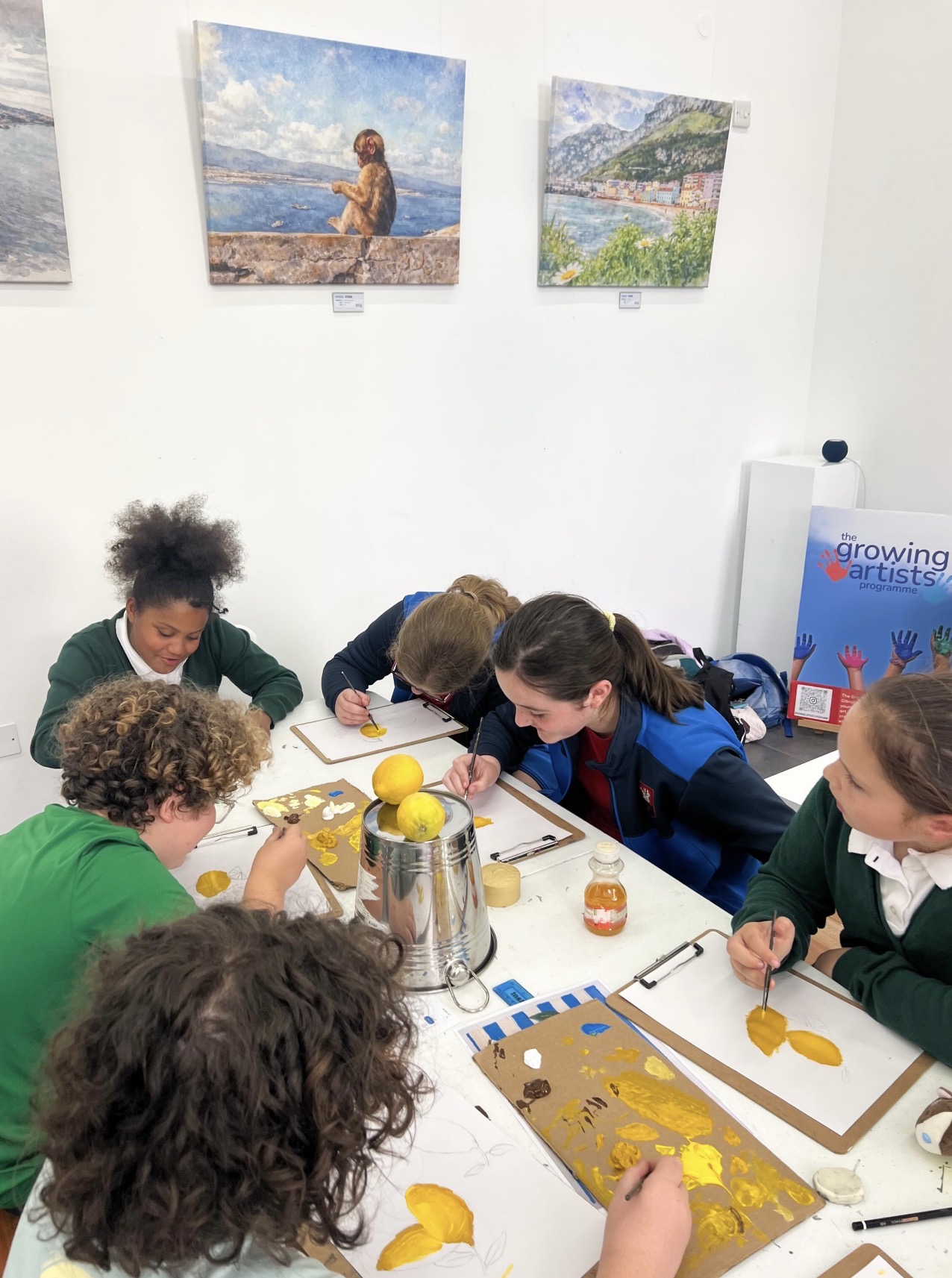 ARTeam students painting still-life studies of lemons around a shared table