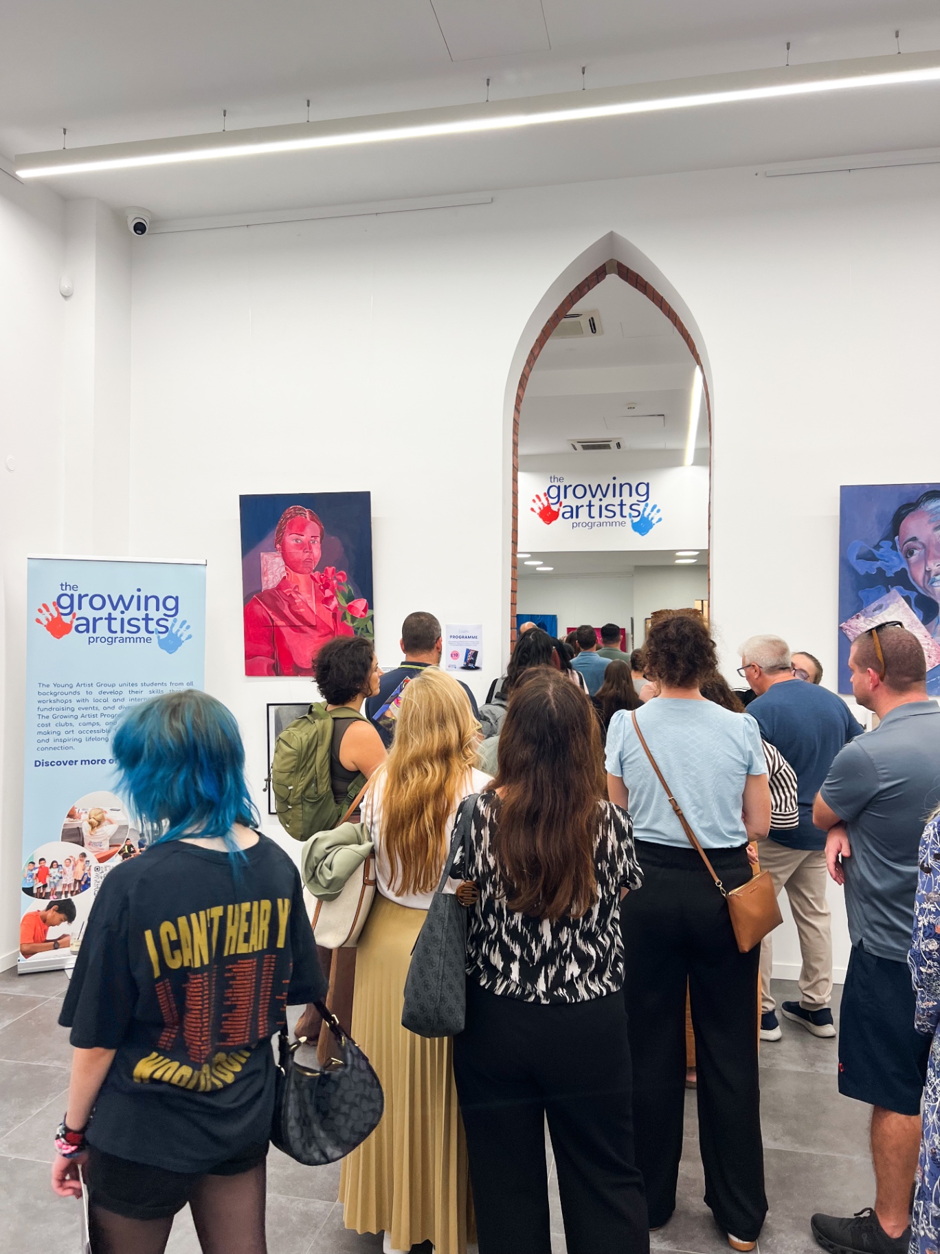 Visitors gathered at an exhibition opening inside the hub, with artwork on the white walls
