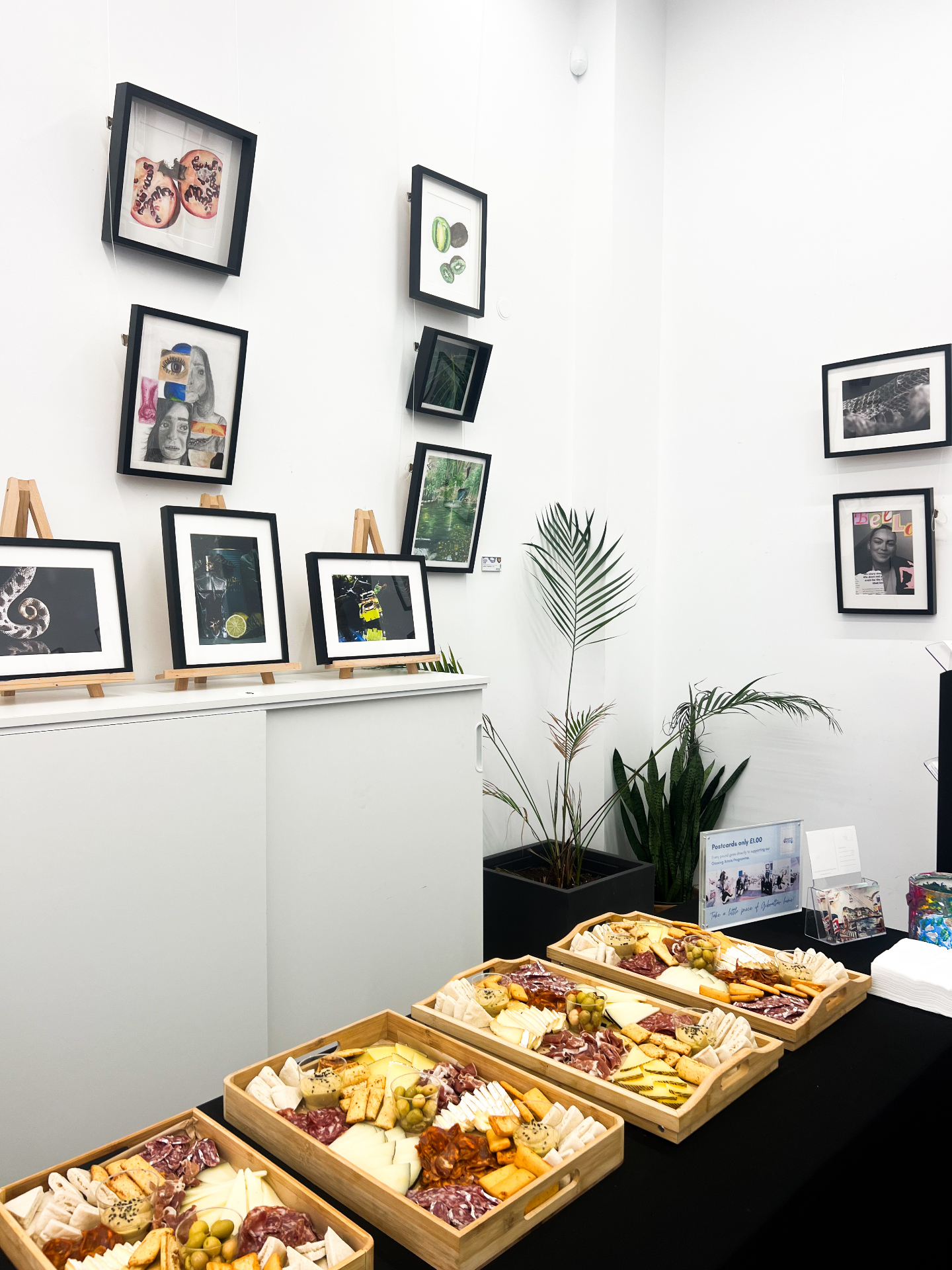 Catering spread of cheese and charcuterie boards beside framed prints at an event