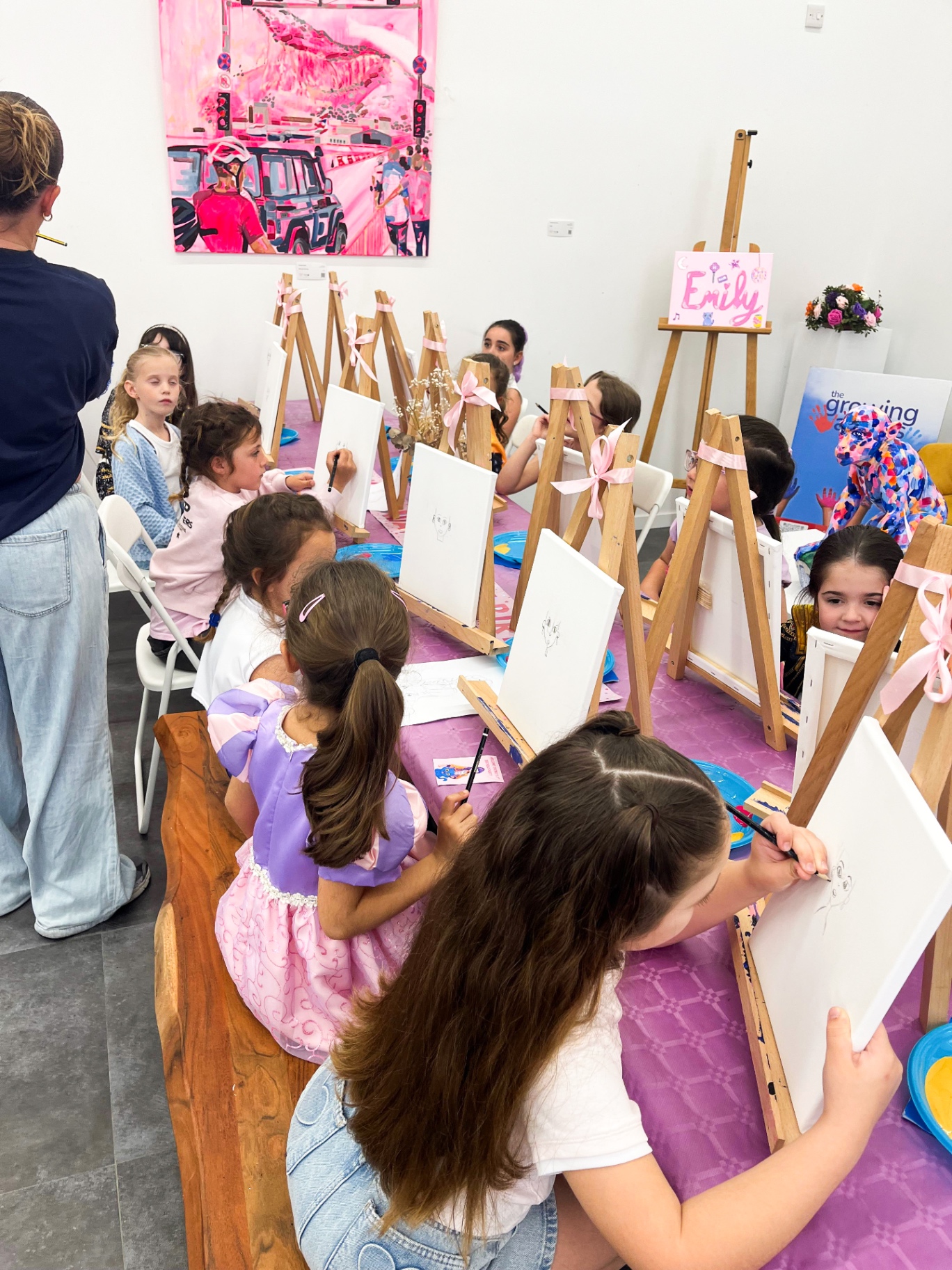Children painting their canvases at easels during an art birthday party