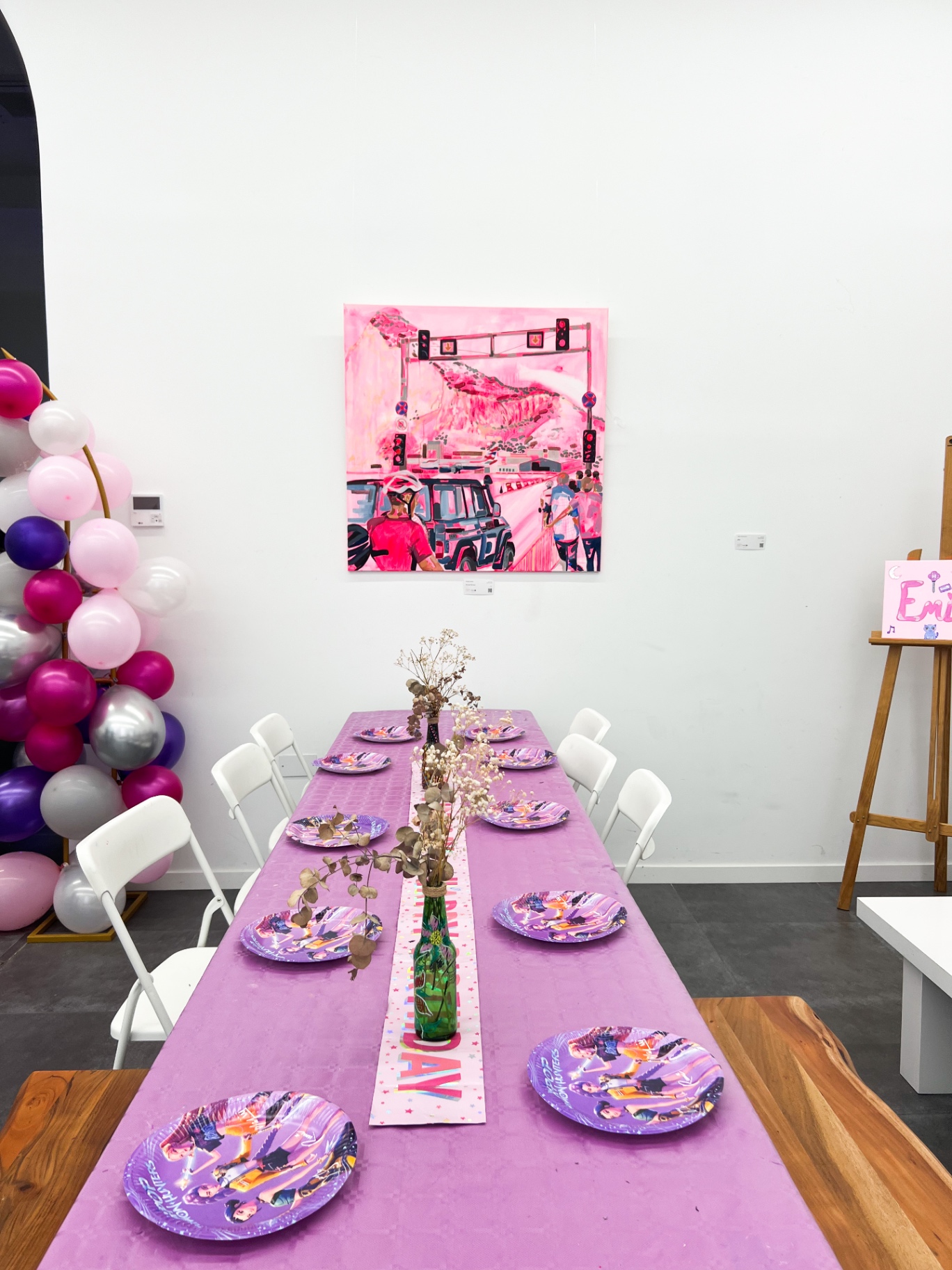 Long party table dressed in a lilac cloth with themed paper plates and a birthday banner runner
