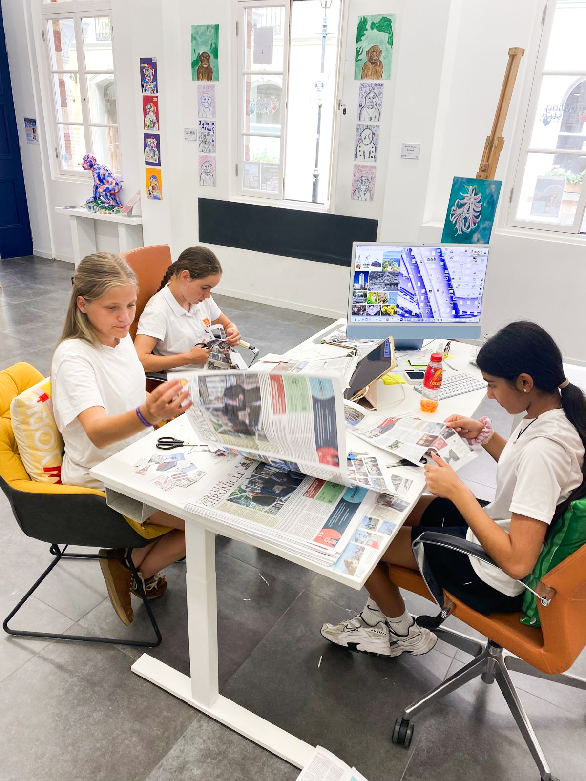 Young artists gathering reference imagery from newspapers for Nelson's design