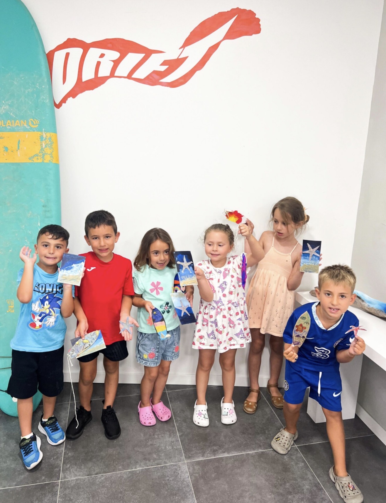 Children from the Art Squad class holding up their handmade artworks